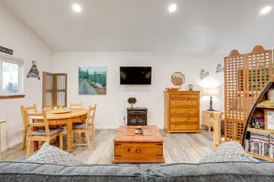 a living room with a couch and a table at Cozy Cottage with Park Pass, 1 Mi to Jenkinson Lake! in Pollock Pines