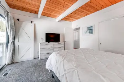 a white bedroom with a bed and a tv at 1 Mi to Lake Tahoe Condo with Pool Access in Kings Beach