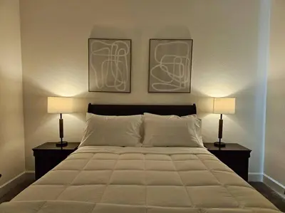 a bedroom with a large bed with two lamps at Couple's Getaway Kitchenette Washer & Private Bath in Lincoln Village