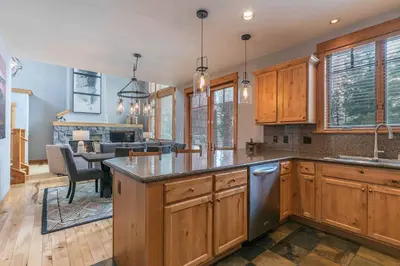 a kitchen with wooden cabinets and a dining room at The Cottages - Ski Shuttle, Ski Valet - 2-Bedroom in Truckee