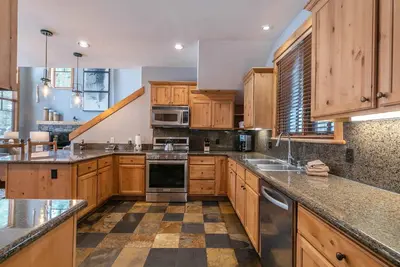 a large kitchen with wooden cabinets and stainless steel appliances at The Cottages - Ski Shuttle, Ski Valet - 3-Bedroom in Truckee