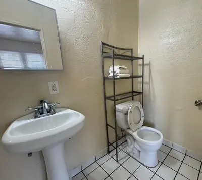 a bathroom with a sink and a toilet and a mirror at The Oaks Motel in Gilroy