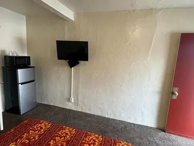 a hotel room with a flat screen tv on a wall at The Oaks Motel in Gilroy