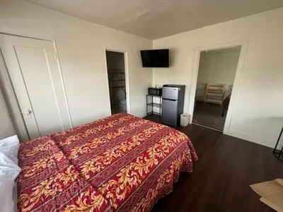 a hotel room with a bed with a red blanket at The Oaks Motel in Gilroy