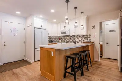 a kitchen with white cabinets and a island with bar stools at Fully Renovated! St Anton #17 Ski in Ski Out 1 Bedroom 1 Bathroom Condo! Sleeps up to 4! in Mammoth Lakes