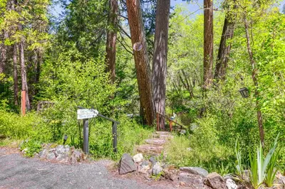 a sign next to a path in a forest at On-Site River Access Quiet Home in Wilseyville! in Wilseyville