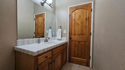 a bathroom with a sink and a mirror at Knotty Pine Cabin with Artisan Stone Patio - Walk to Bass Lake in Bass Lake
