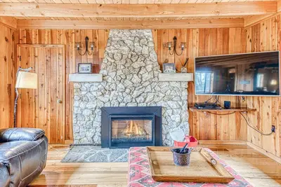 a living room with a stone fireplace and a couch at Baxter Mountain Cottage in Shaver Lake