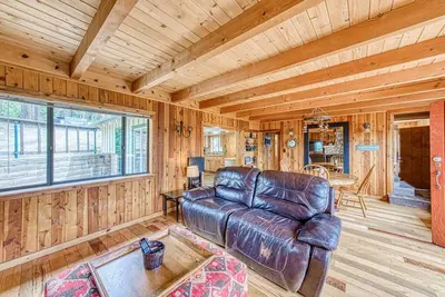 a living room with a leather couch and a table at Baxter Mountain Cottage in Shaver Lake
