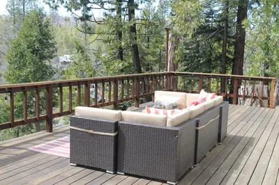a wicker couch sitting on a wooden deck at Baxter Mountain Cottage in Shaver Lake