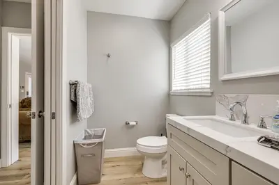 a white bathroom with a toilet and a sink at Quaint Hughson Vacation Rental, Walk to Downtown! in Hughson