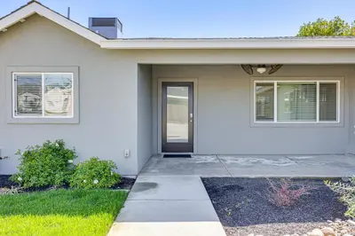 a white house with a door and windows at Quaint Hughson Vacation Rental, Walk to Downtown! in Hughson