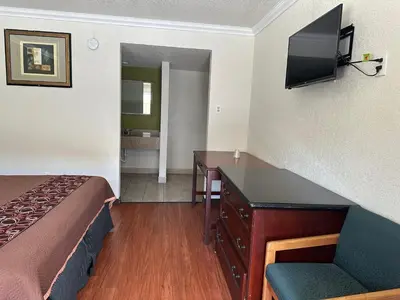 a hotel room with a bed and a desk and a television at Regency Inn Fresno in Fresno