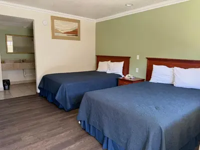 a hotel room with two beds and a bathroom at Regency Inn Fresno in Fresno