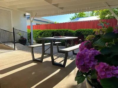 a picnic table and benches on a patio with purple flowers at Spacious 2Beds Suite Close to Downtown and UC Davis Medical Center in Sacramento