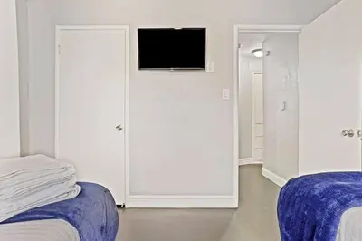 a white room with two beds and a tv on a wall at Robert St Cottage, near Lodi Lake in Lodi