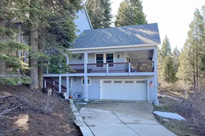 a white house with a balcony and a garage at Under The Stars in Shaver Lake