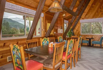 a dining room with a table and chairs in a cabin at Quail Haven- A-frame cabin with hot tub, views, and more in Oakhurst