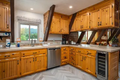 a large kitchen with wooden cabinets and a window at Quail Haven- A-frame cabin with hot tub, views, and more in Oakhurst
