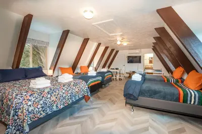 a room with three beds and a dining room with a table at Quail Haven- A-frame cabin with hot tub, views, and more in Oakhurst