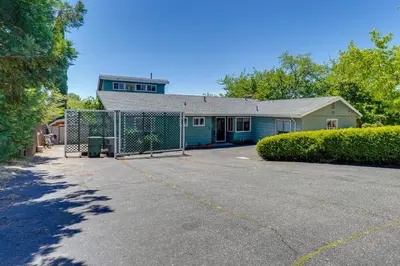 a house with a fence in front of a driveway at Auburn Cottage with Patios and Garden - 3 Mi to Town! in Auburn