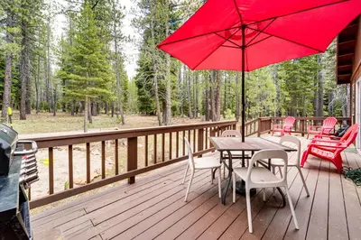 a wooden deck with a table and chairs with a red umbrella at Home with Deck and Access to Tahoe Donner Amenities! in Truckee