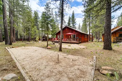 a red cabin in the woods with a large yard at Home with Deck and Access to Tahoe Donner Amenities! in Truckee
