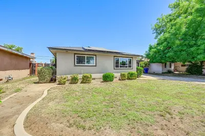 a house with a large yard in front of it at Family-Friendly Clovis Home with Gas Grill and Patio! in Clovis