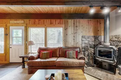 a living room with a leather couch and a stone fireplace at Tranquil Family Cabin in Incline Village