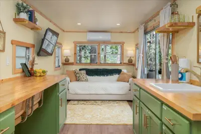 a kitchen with green cabinets and a couch at Tiny home with spa/firepit/and more in Oakhurst