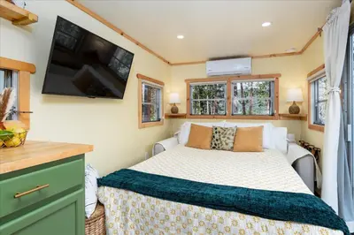 a bedroom with a bed and a tv on the wall at Tiny home with spa/firepit/and more in Oakhurst
