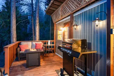 a screened in porch with a grill on a deck at Tiny home with spa/firepit/and more in Oakhurst