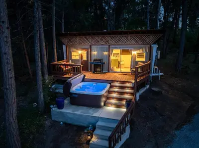 a small cabin with a hot tub on a deck at Tiny home with spa/firepit/and more in Oakhurst