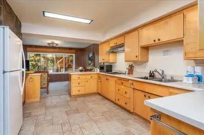 a kitchen with wooden cabinets and a white refrigerator at River's Edge w/ BBQ, Wifi, Firepit in North Wawona