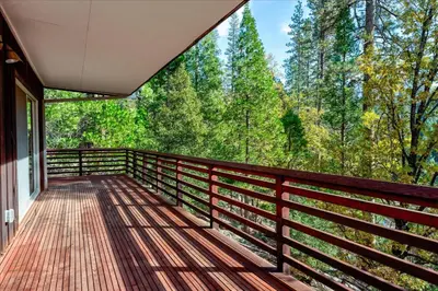 a balcony of a house with a view of the forest at River's Edge w/ BBQ, Wifi, Firepit in North Wawona