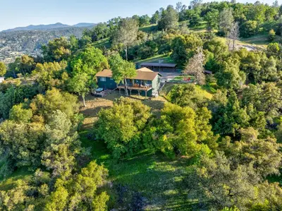an aerial view of a house on a hill with trees at Vista Haven with stunning views/hot tub/mini golf in Oakhurst