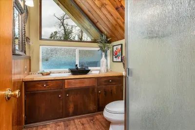 a bathroom with a toilet and a window at Bass Lake Chalet- A frame with hot tub/firepit in Oakhurst