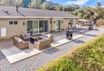 a patio with wicker furniture and a grill at Mountain View House with hot tub, putting green, stunning views in Oakhurst