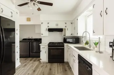 a white kitchen with black appliances and a ceiling fan at Homey Pool Fun Gameroom Sunnyside Retreat in Fresno