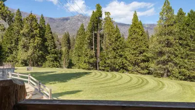 a field of grass with trees and mountains in the background at Suite Meadow @CN Lodge# 7 in Ponderosa