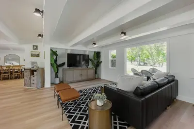 a living room with a black leather couch and a tv at Lakefront Cottage at Lakewood in Auburn