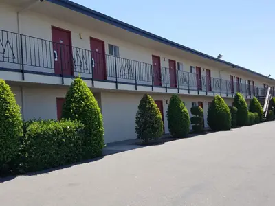 a building with a row of bushes in front of it at Economy Inn Fresno Yosemite in Fresno