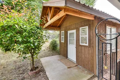 a small wooden shed with a white door and a tree at Yosemite Wellbeing Retreat on 5 Acres with Mtn Views in Ahwahnee