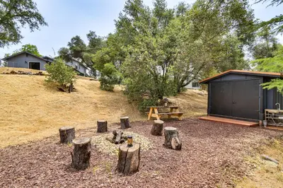 a group of logs in a yard with a building at Yosemite Wellbeing Retreat on 5 Acres with Mtn Views in Ahwahnee