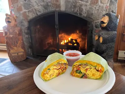 two breakfast burritos on a plate in front of a fireplace at Camp Richardson Resort in South Lake Tahoe