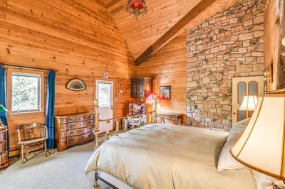 a bedroom with a bed and a stone wall at Game Room and Hot Tub Serene Grand Mountain Chalet! in Stateline