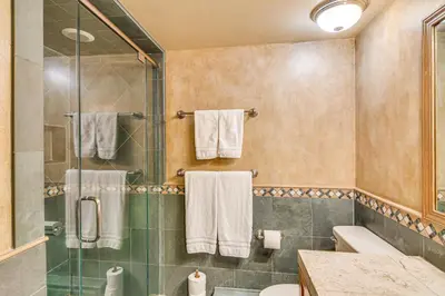 a bathroom with a shower and a toilet and towels at Game Room and Hot Tub Serene Grand Mountain Chalet! in Stateline