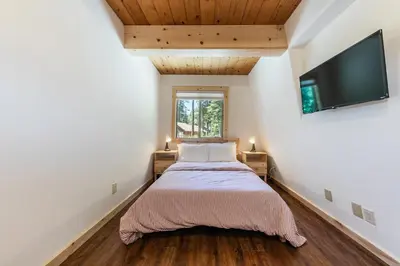 a bedroom with a bed and a flat screen tv at 10th Mountain Home - 4BR Tahoe Donner w Hot Tub, HOA amenities! in Truckee