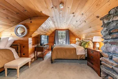 a bedroom with two beds and a stone wall at Reflections Lakeview Cabin - Private Beach Access, Hot Tub & Buoy! in Carnelian Bay