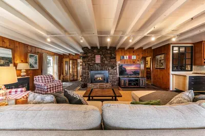 a living room with two couches and a stone fireplace at Reflections Lakeview Cabin - Private Beach Access, Hot Tub & Buoy! in Carnelian Bay